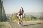 woman in black tank top riding bicycle on road